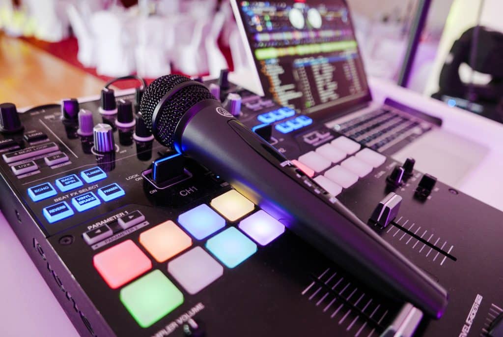 Close-up image of DJ equipment with mixer, microphone and laptop.