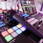 Close-up image of DJ equipment with mixer, microphone and laptop.