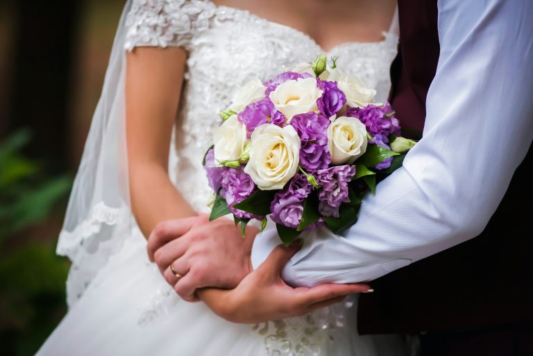 bride and groom with a beautiful bouquet are hugging in the summer at a wedding close-up