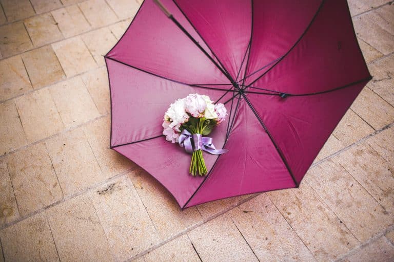 Pink wedding bouquet next to a red umbrella a rainy wedding day, nice melancholic photo.