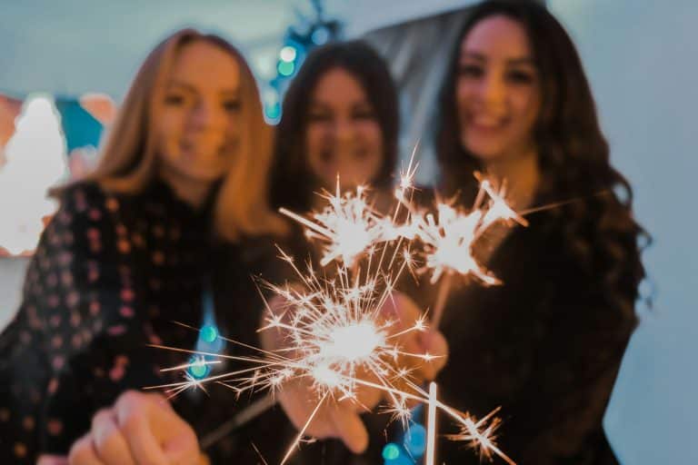 Tree girls, friends celebrating new year together. WInter holiday party. Bengal light in focus. Chri